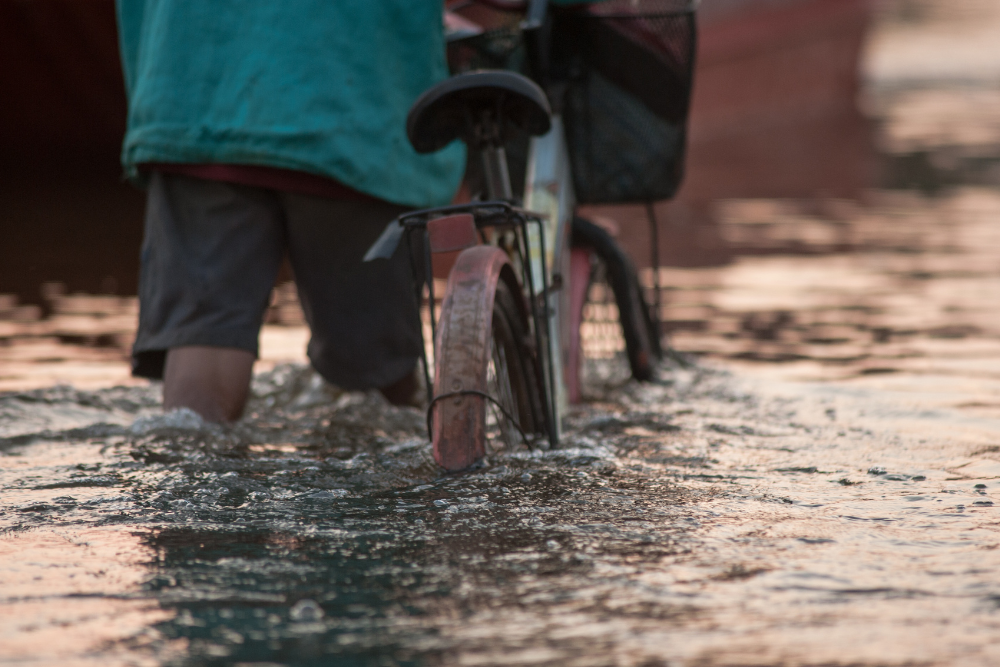 洪水の中自転車を押す人